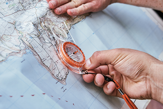 Close up of a person using a compass with a map