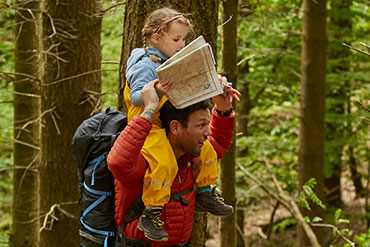 Child holding a map riding on parents shoulders